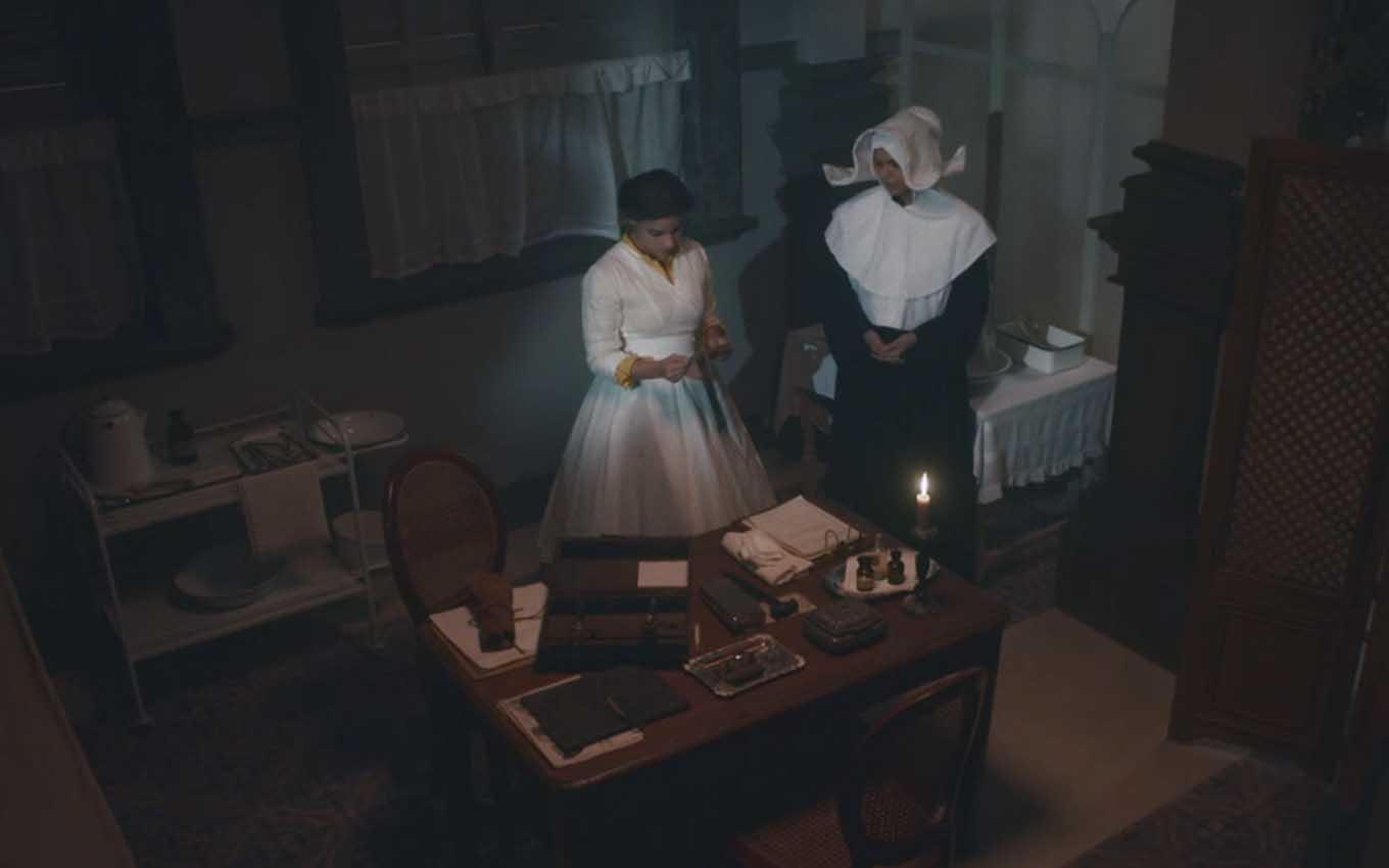 A atriz Gabriela Medvedovski, como Pilar, lê um bilhete ao lado de uma freira em uma tomada aérea de Nos Tempos do Imperador