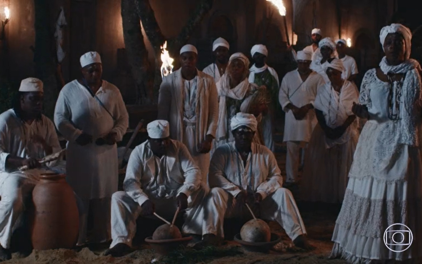 Em cena noturna, moradores da Pequena África, vestidos de branco, batem em atabaques e cantam em Nos Tempos do Imperador