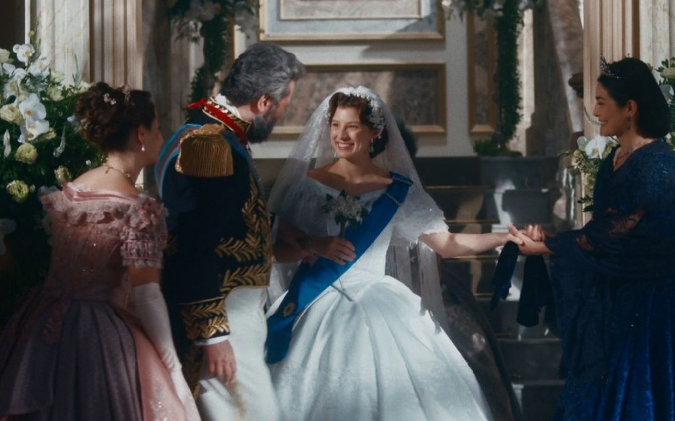 Isabel (Giulia Gayoso) está vestida de noiva ao lado dos pais e da irmã