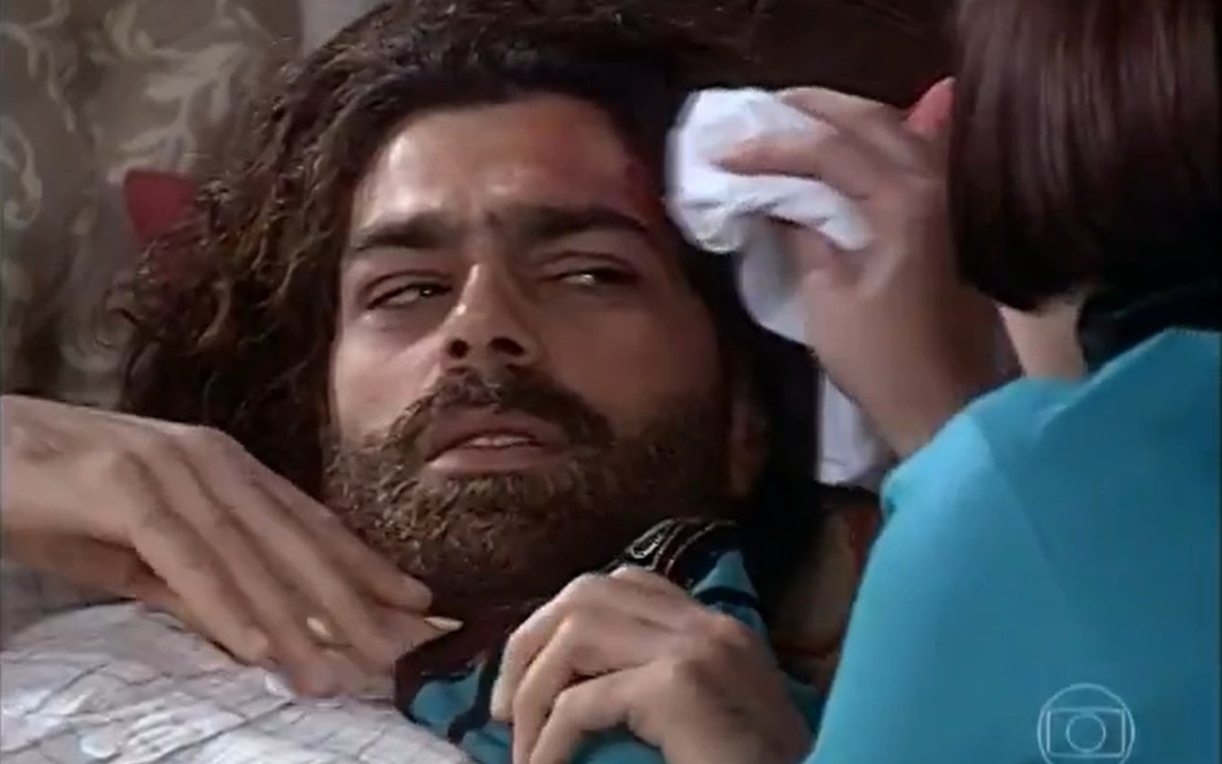 Eduardo Moscovis, caracterizado como Petruchio, olha surpreso para Adriana Esteves, a Catarina, que limpa seu machucado em cena de O Cravo e a Rosa