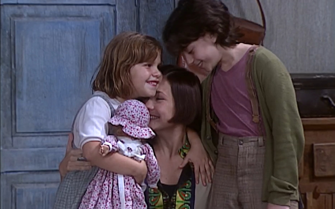 Catarina (Adriana Esteves) abraça Fátima (Thais Müller) e Jorginho (João Cappelli) em cena de O Cravo e a Rosa