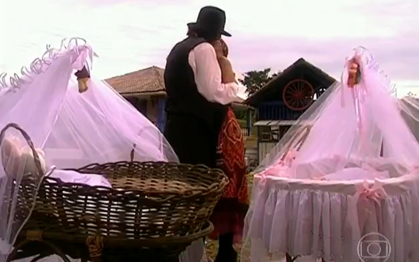 Eduardo Moscovis, caracterizado como Petruchio, e Adriana Esteves, a Catarina, se beijam atrás dos cestos dos bebês em cena de O Cravo e a Rosa