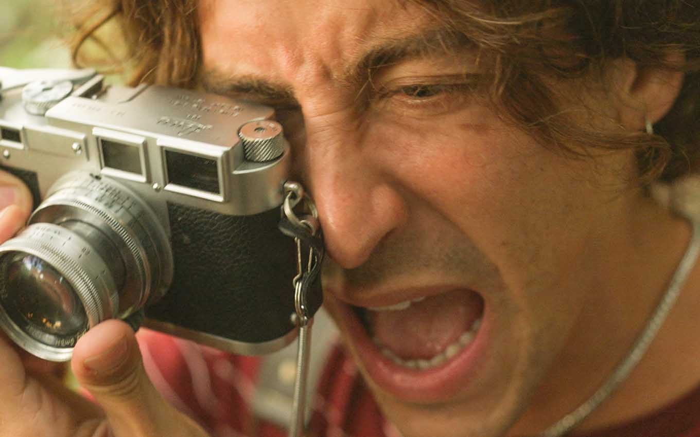 O ator Jesuita Barbosa faz cara de dor com uma câmera fotográfica em mãos em cena de Pantanal