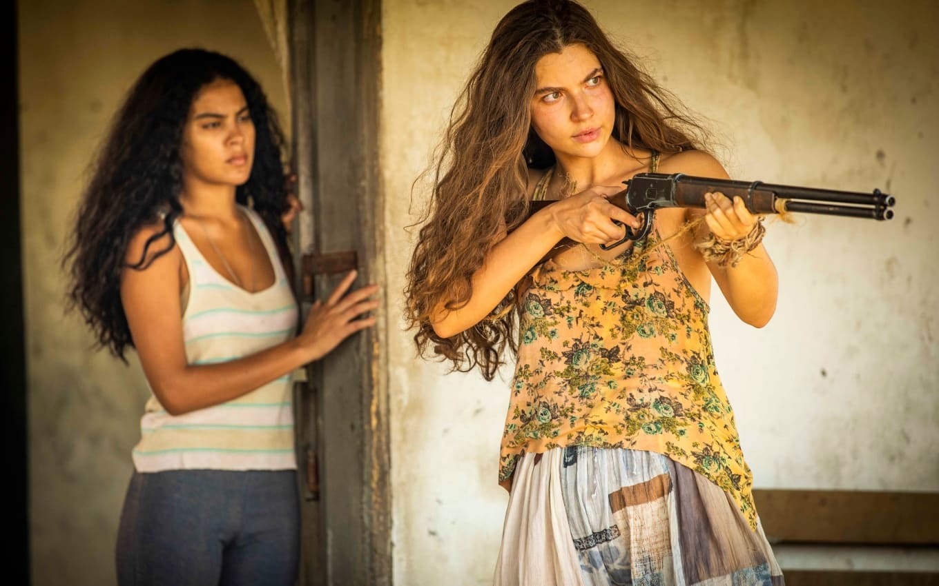 Muda (Bella Campos) e Juma (Alanis Guillen) em Pantanal; a filha de Maria Marruá (Juliana Paes) aponta a espingarda para Tibério (Guito)