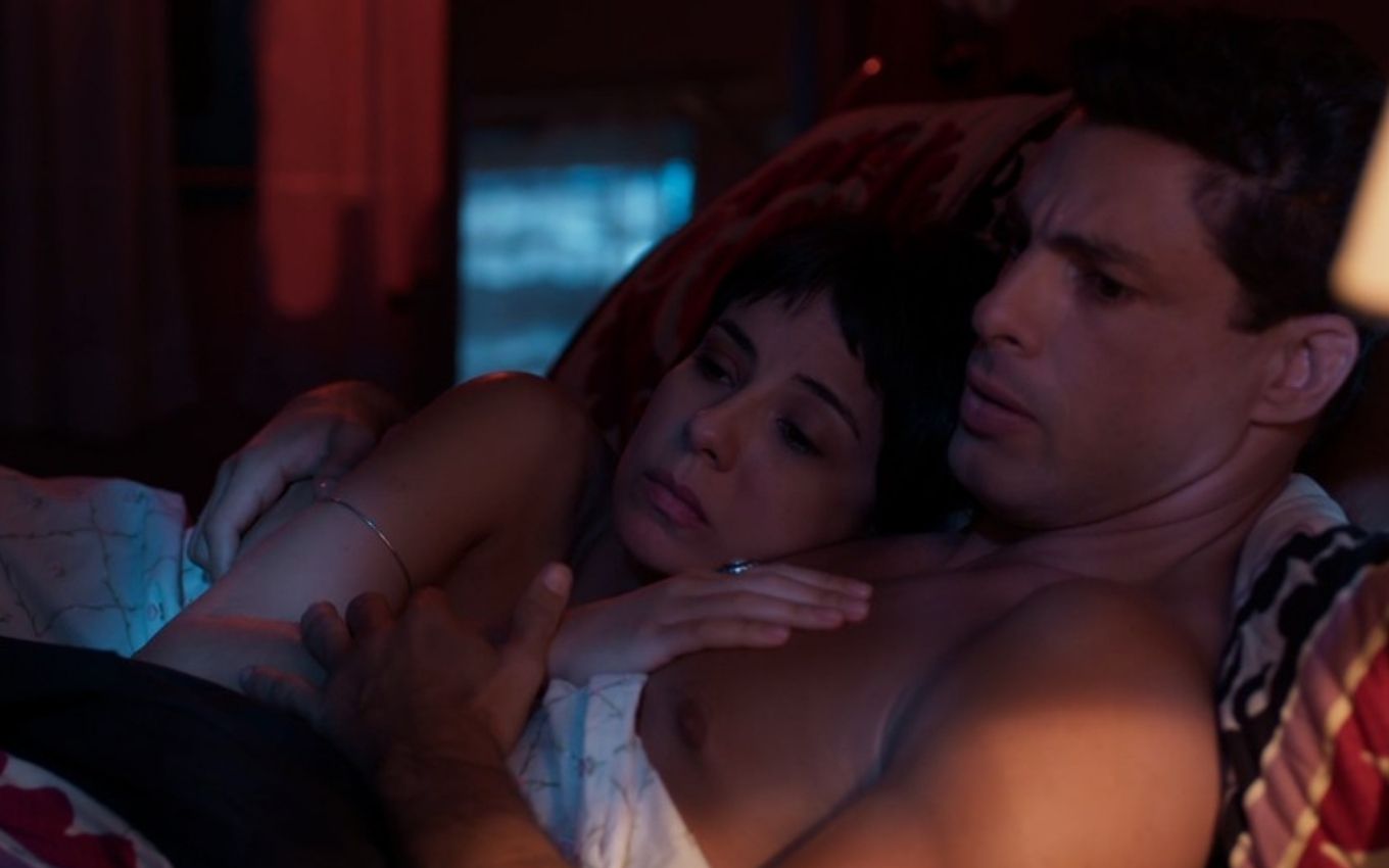 Christian/Renato e Lara estão deitados em cama abraçados