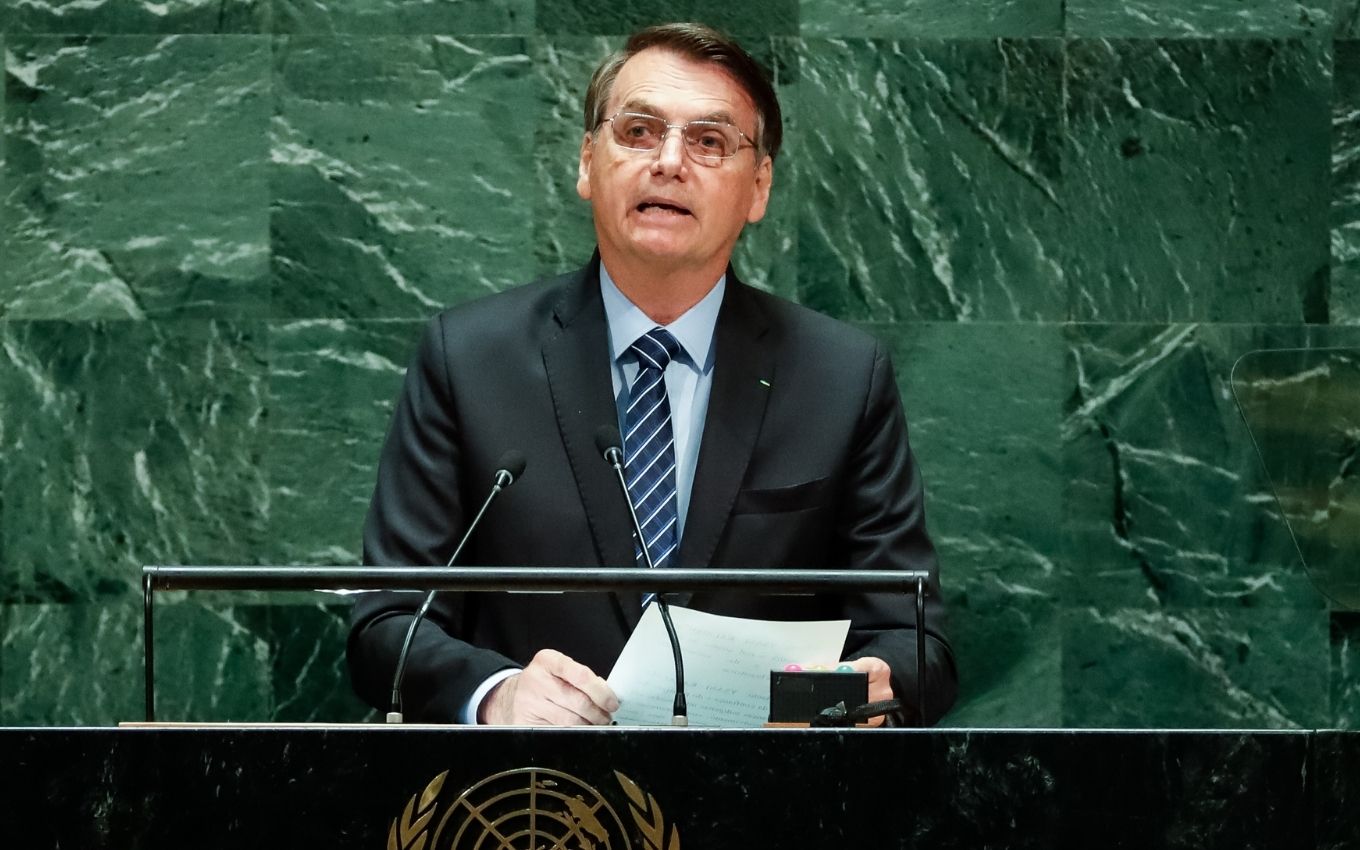 O presidente Jair Bolsonaro segura um papel e faz um discurso no plenário da ONU em Nova York