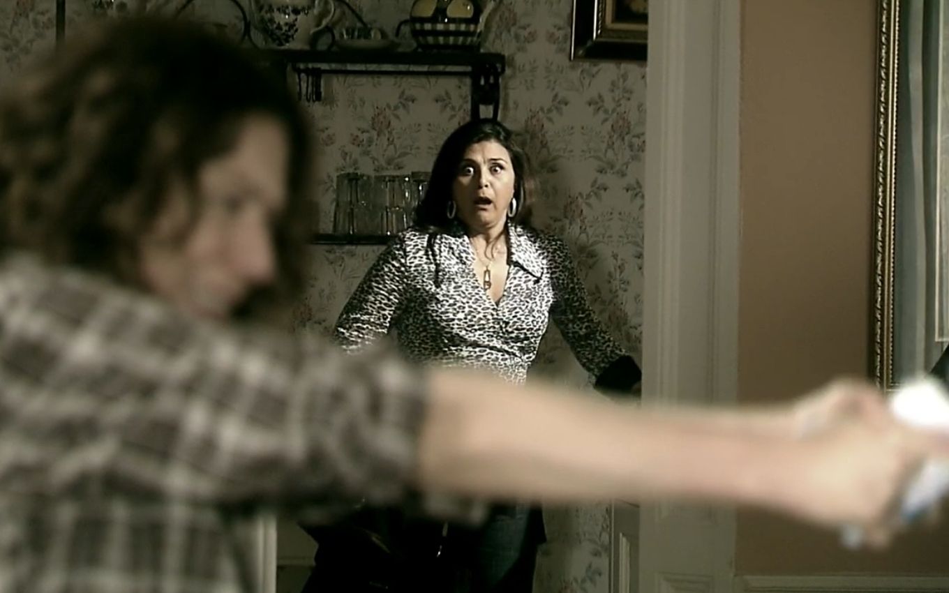 Patrícia Pillar aponta arma; Elizangela ao fundo vê a cena