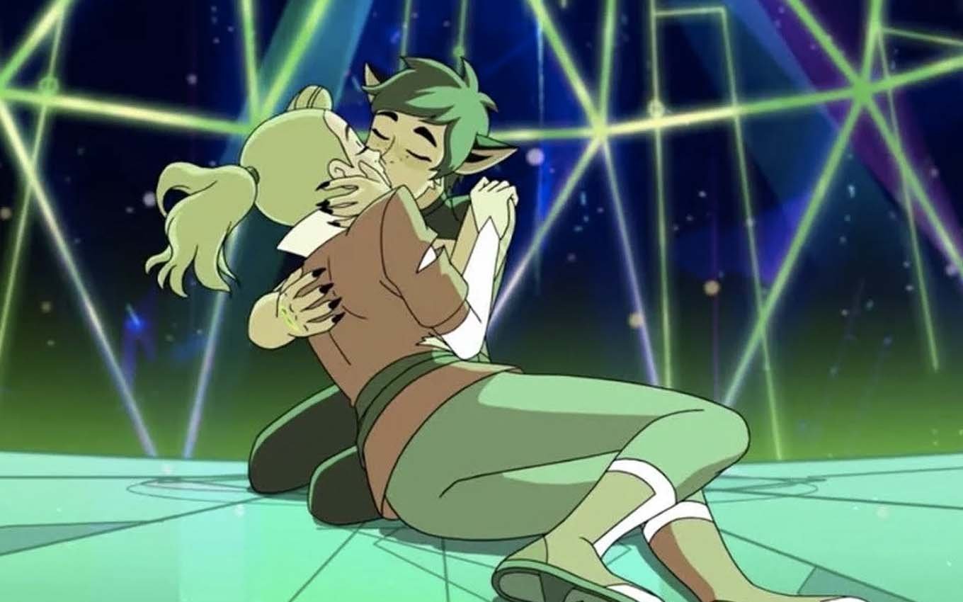 As personagens Adora e Catra se beijam no chão de uma espaçonave em She-Ra
