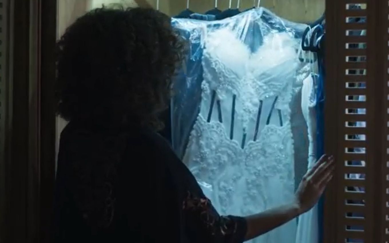 De costas, Rose olha para vestido branco dentro do armário