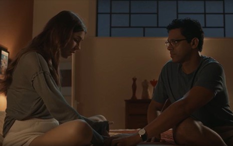 Em cena de Renascer, Renan Monteiro e Gabriela Medeiros estão sentados na cama